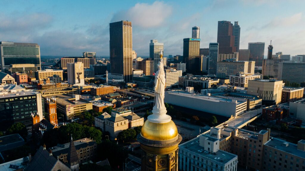 A stunning aerial view of the Atlanta skyline with iconic landmarks and urban landscape under a blue sky.